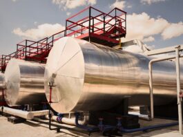 OPEC+ oil production increase shown through large petroleum storage tanks at a global refinery.